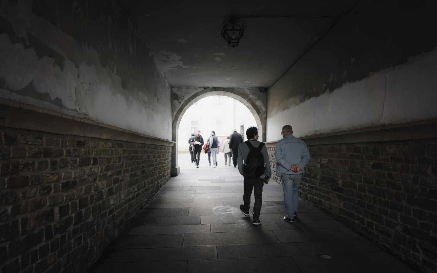 Personas atravesando un túnel transitable que desemboca en la Praza dos Bombeiros.