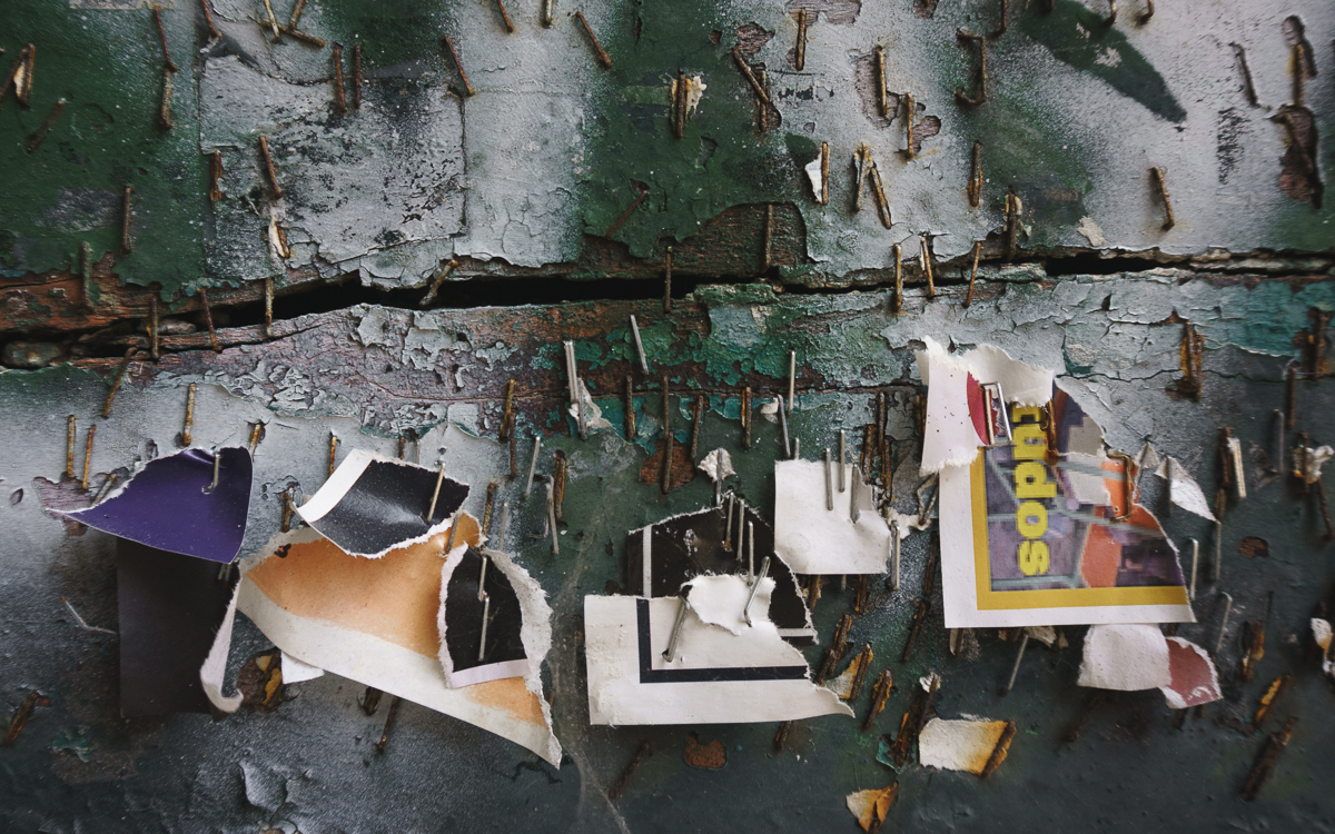 Composición artística de ventana de calle, repleta de grapas con requicios de carteles publicitarios