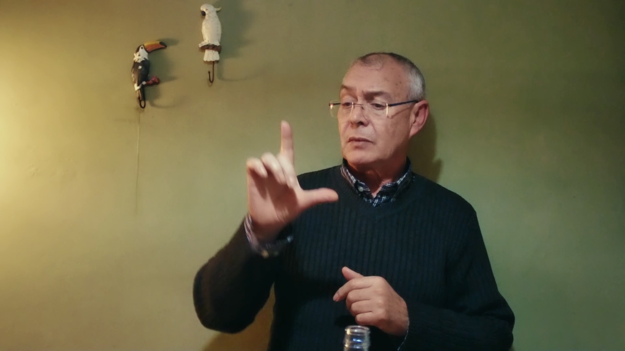 Un hombre está signando la letra L. 