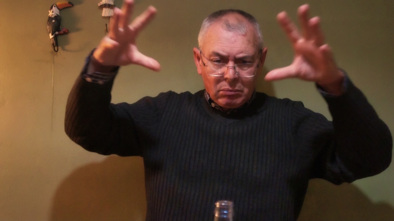 Plano medio de hombre gesticulando con brazos en alto y palmas extendidas.